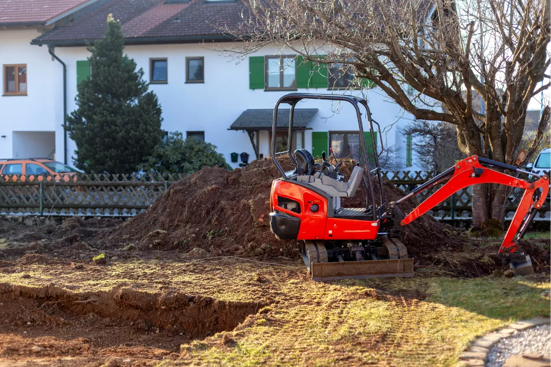 Minigraver i gang med jordarbejde ved et hus